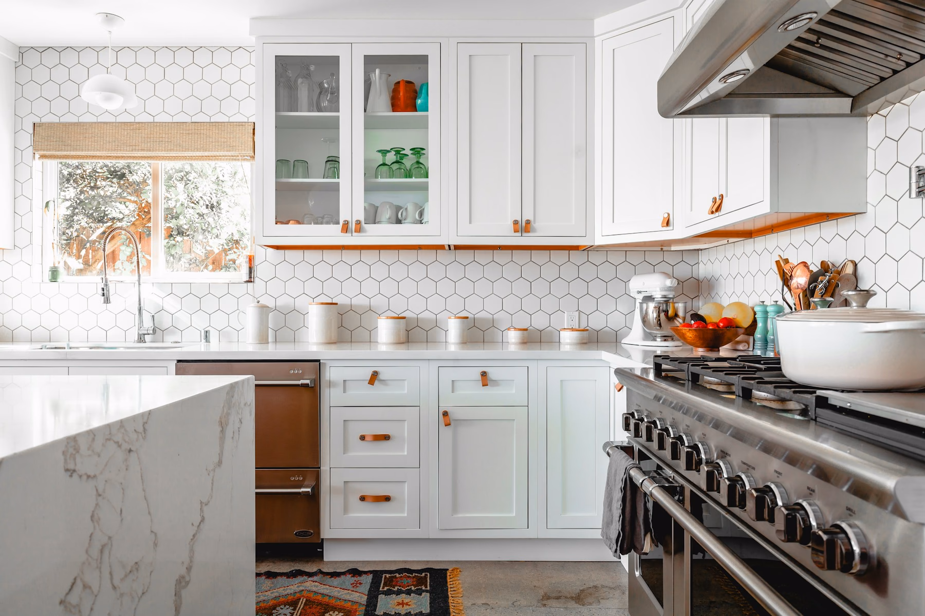 White kitchen with hexagonal tile backsplash, shaker cabinets and a waterfall island