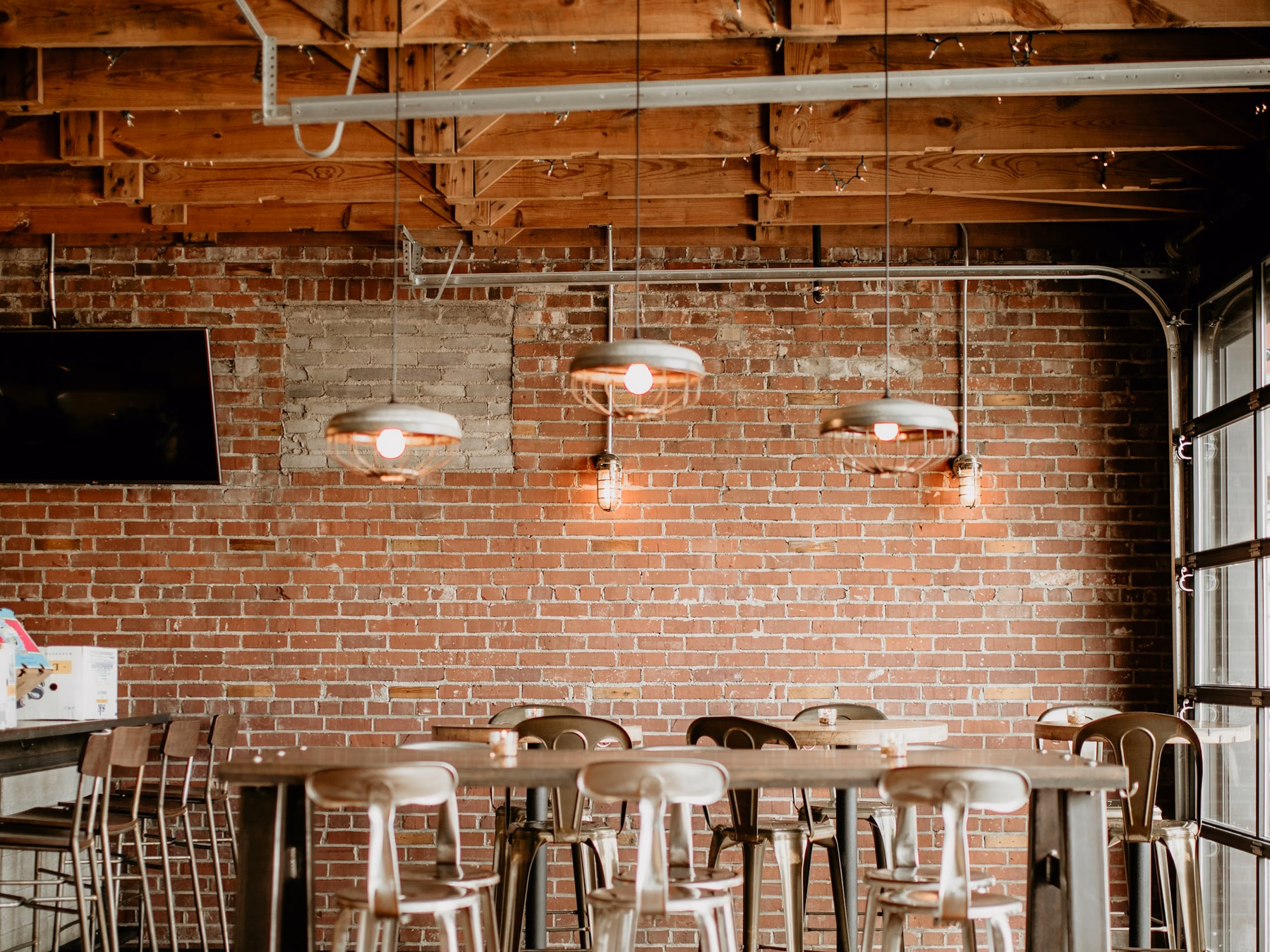 Restaurant dining area with exposed brick, pendant lights and counter-height seating